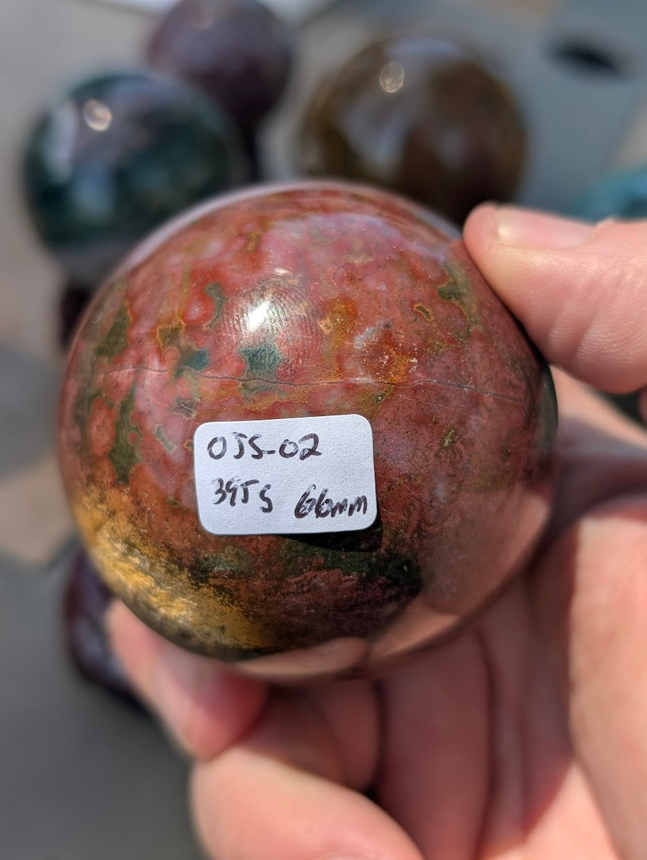 AA-grade 66mm Ocean Jasper sphere from Madagascar showing OJS-02 weight label.