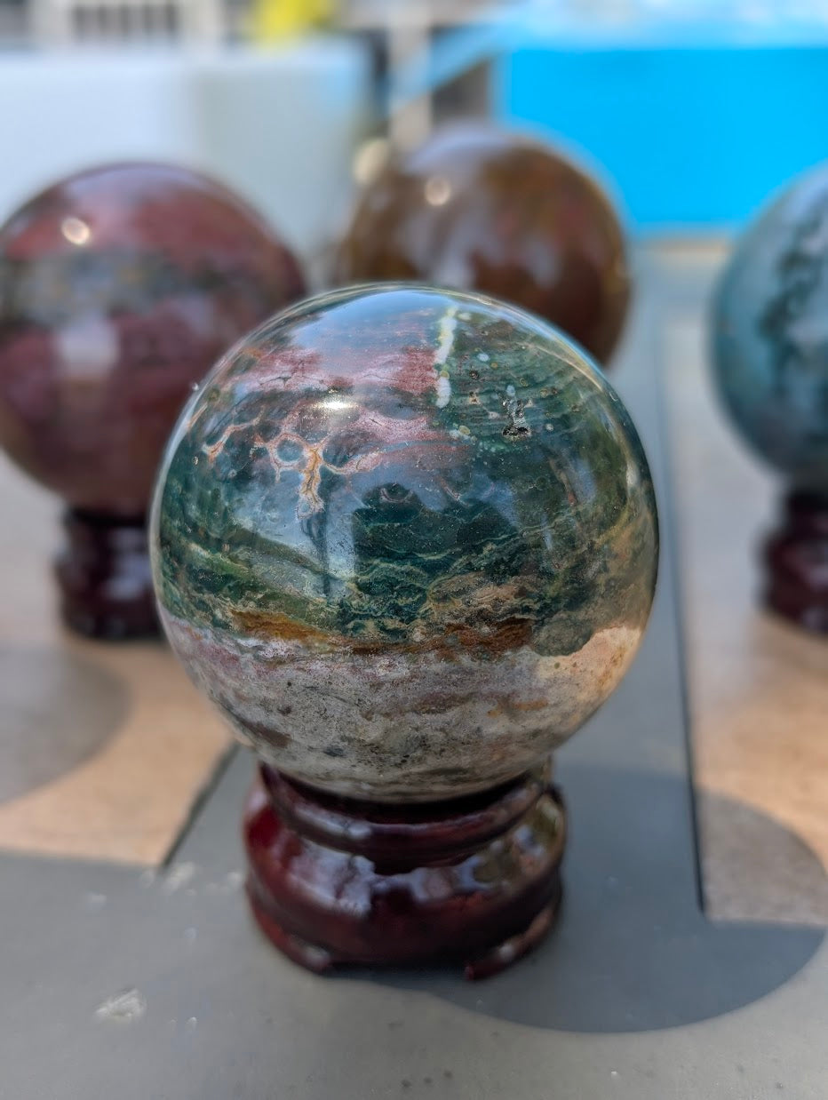 59mm Ocean Jasper sphere showing a high-contrast dark forest green and rust-red matrix.