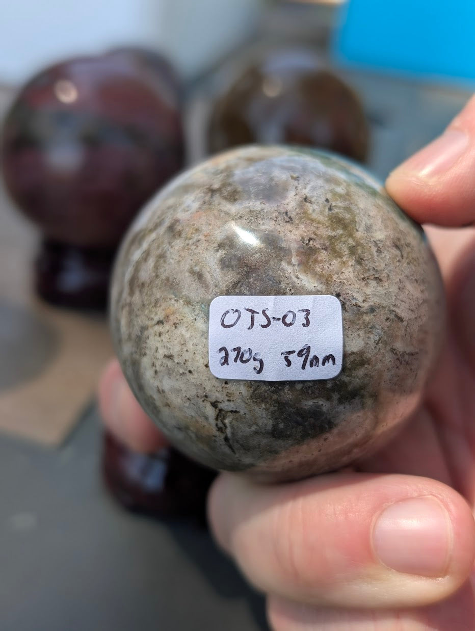 Macro view of 59mm Ocean Jasper sphere featuring vivid white orbicular chalcedony clusters.
