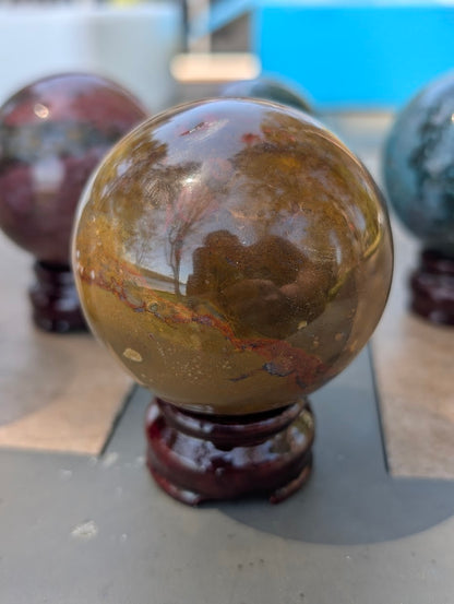 Macro view of 67mm Ocean Jasper sphere highlighting dense mustard and yellow-ochre mineral banding.