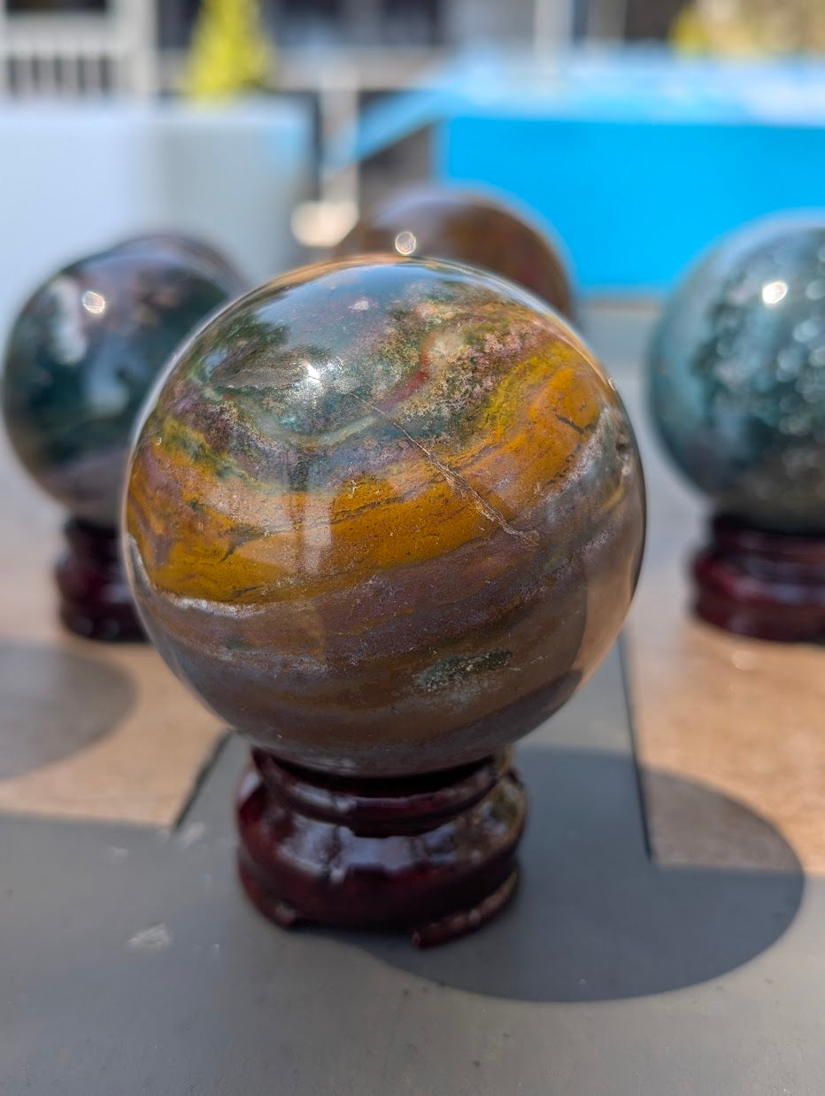 66mm Ocean Jasper sphere featuring dramatic stratified horizontal banding and warm ochre hues.