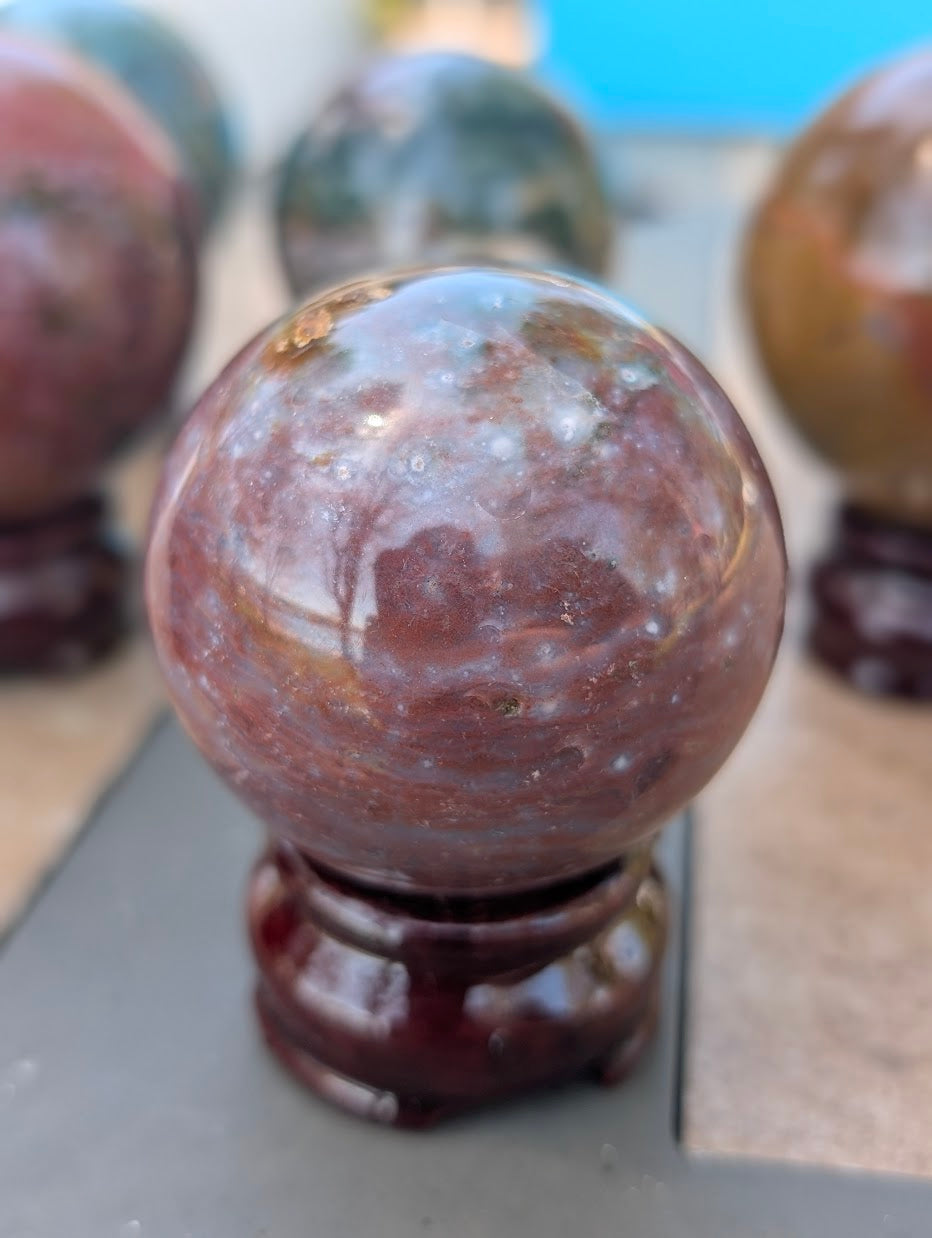 54mm Ocean Jasper sphere with high-contrast orbicular white patterns in a dark mineral matrix.