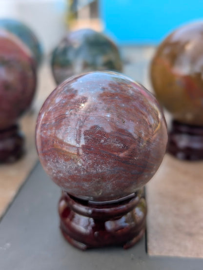 Detail of polished 54mm Ocean Jasper sphere highlighting natural structural vugs.