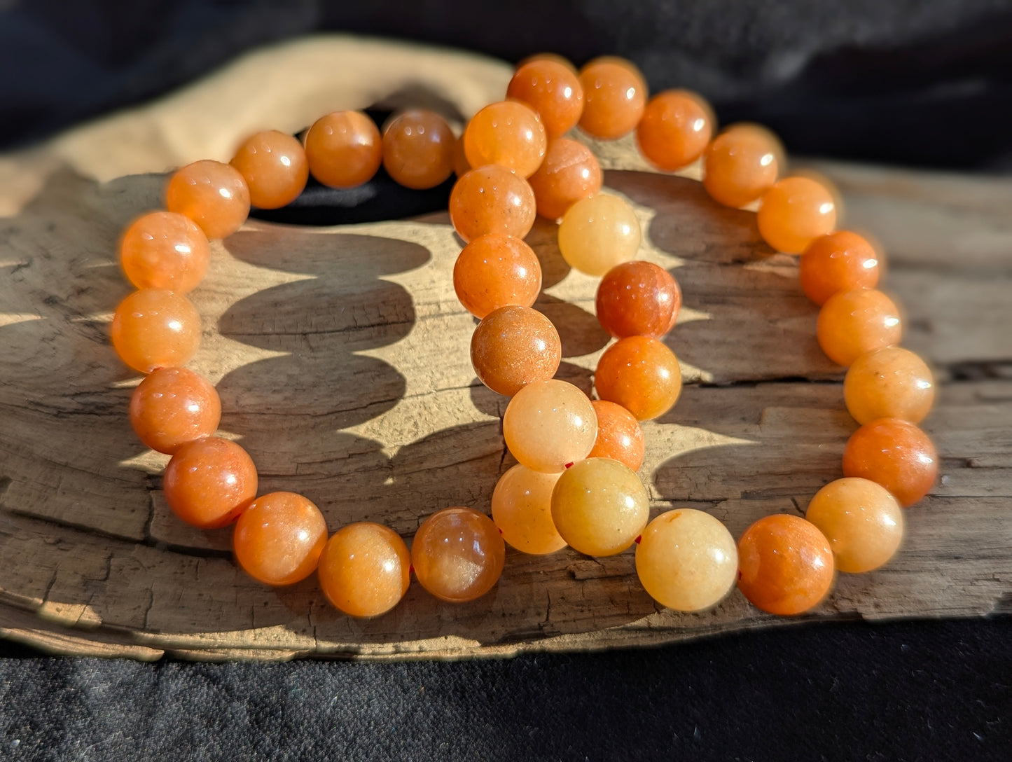 An all-natural 10mm Orange Aventurine round bead stretch bracelet positioned on a neutral presentation surface, demonstrating precise lapidary polish and warm, natural orange mineral saturation.