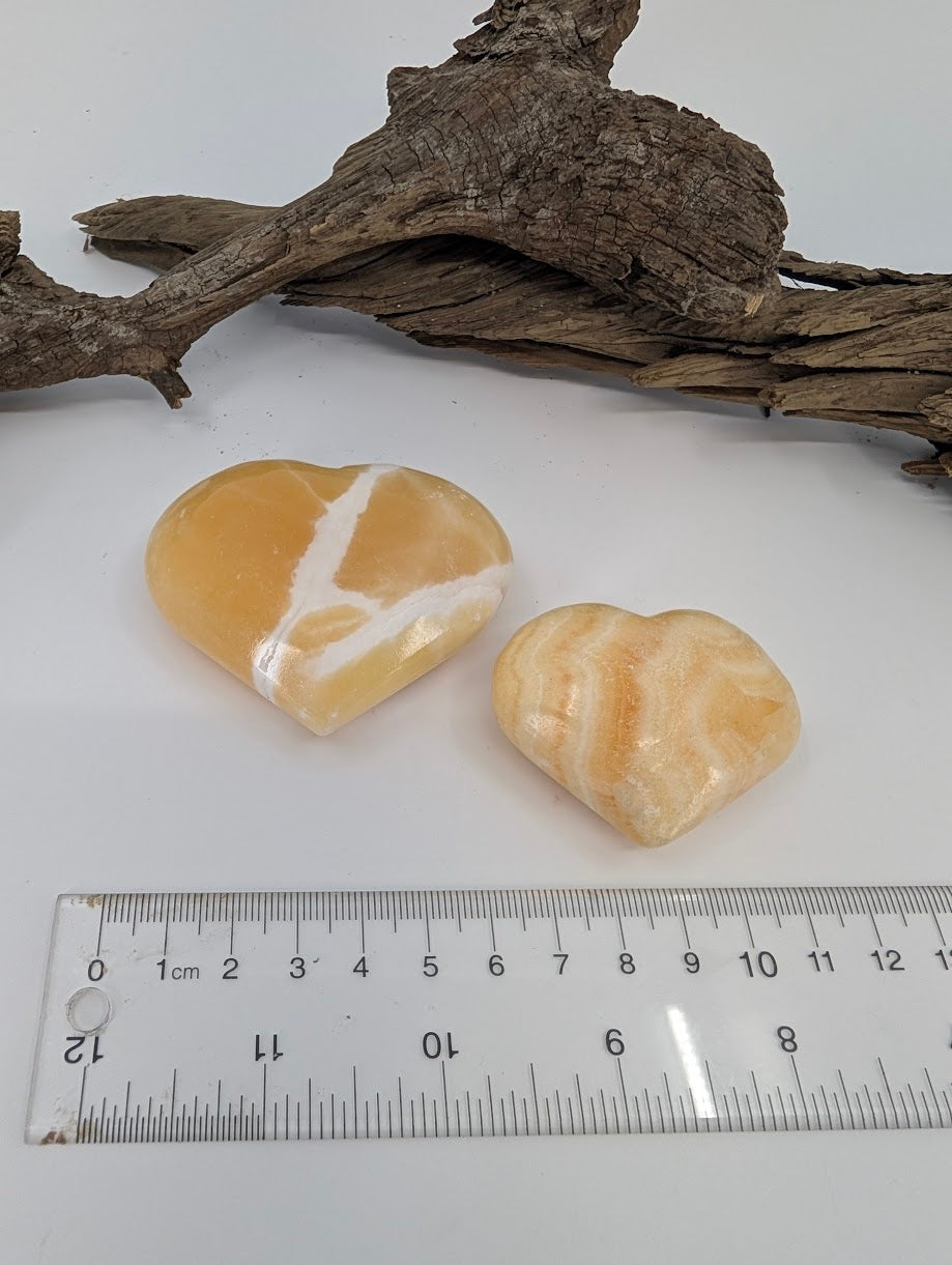 Size comparison of Small and Medium Orange Calcite hearts showing vibrant citrus color.