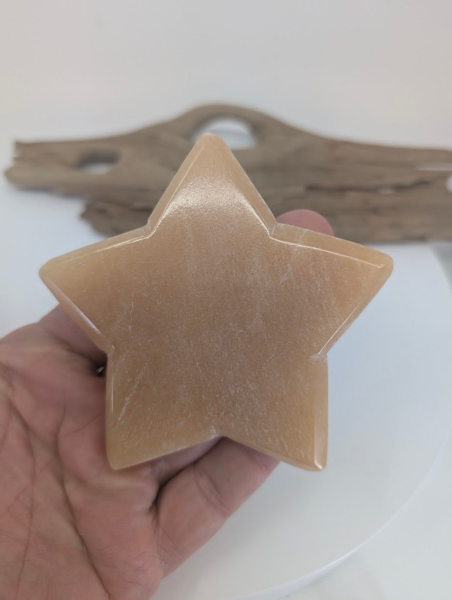 Close-up of a 91mm Orange Calcite star showing the high-luster polished finish, internal white veiling, and natural translucency.