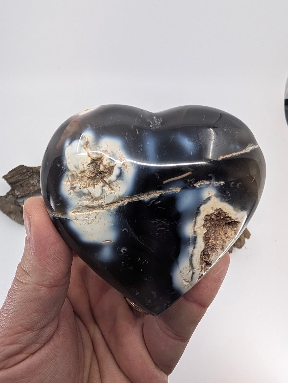 Hand holding Specimen A, a massive 365g Orca Agate heart with white swirls.