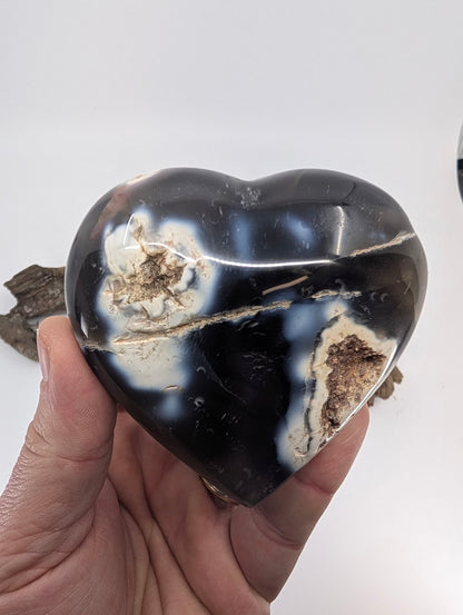 Hand holding Specimen A, a massive 365g Orca Agate heart with white swirls.