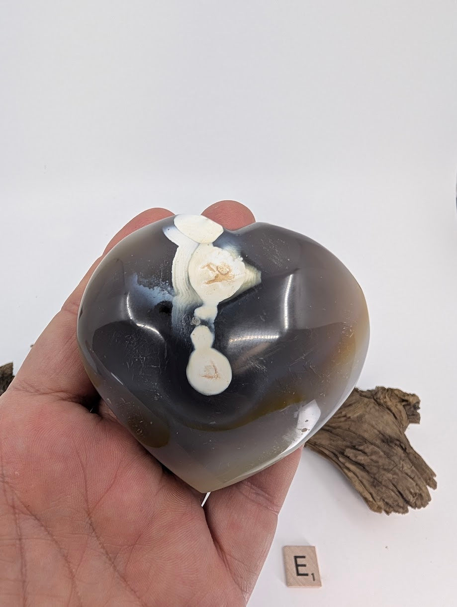 Hand holding Specimen E, a 245g Orca Agate heart with large white center patch.