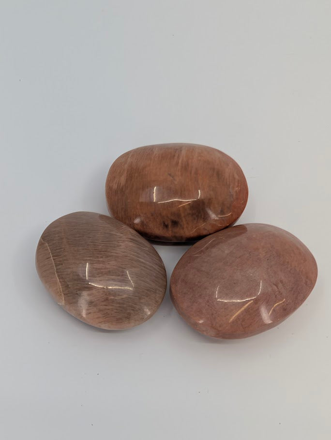 Peach Moonstone palm stones with soft shimmer and warm peach tones, polished surface front view