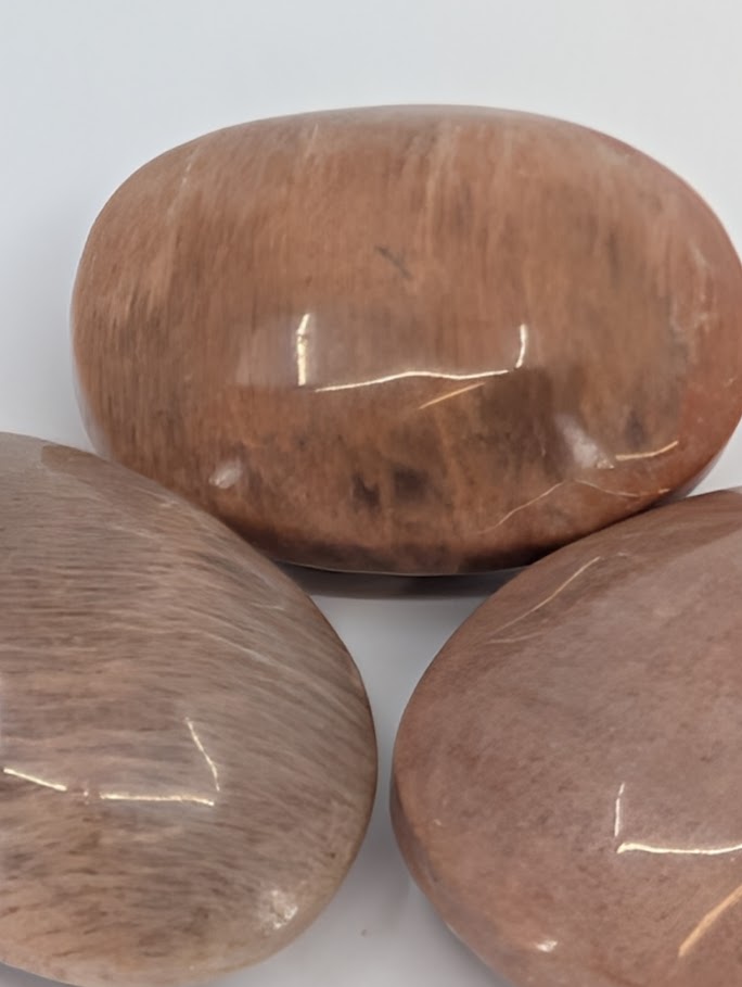 Peach Moonstone palm stones grouped together showing gentle chatoyancy and warm glow