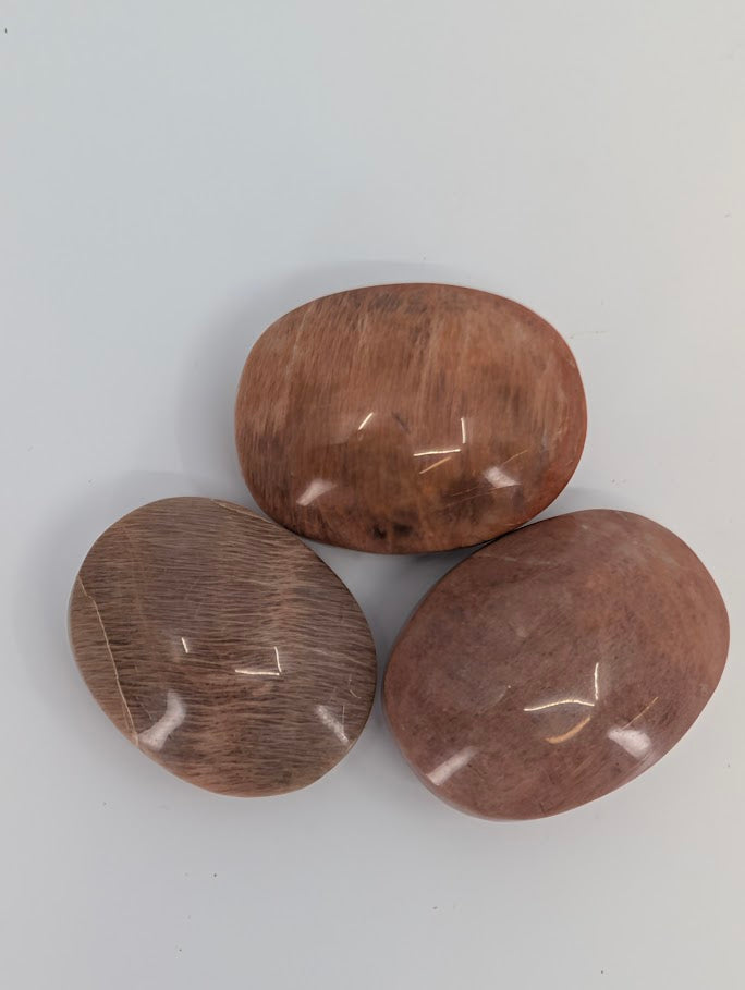 Close-up of Peach Moonstone palm stones displaying natural sheen and smooth polish