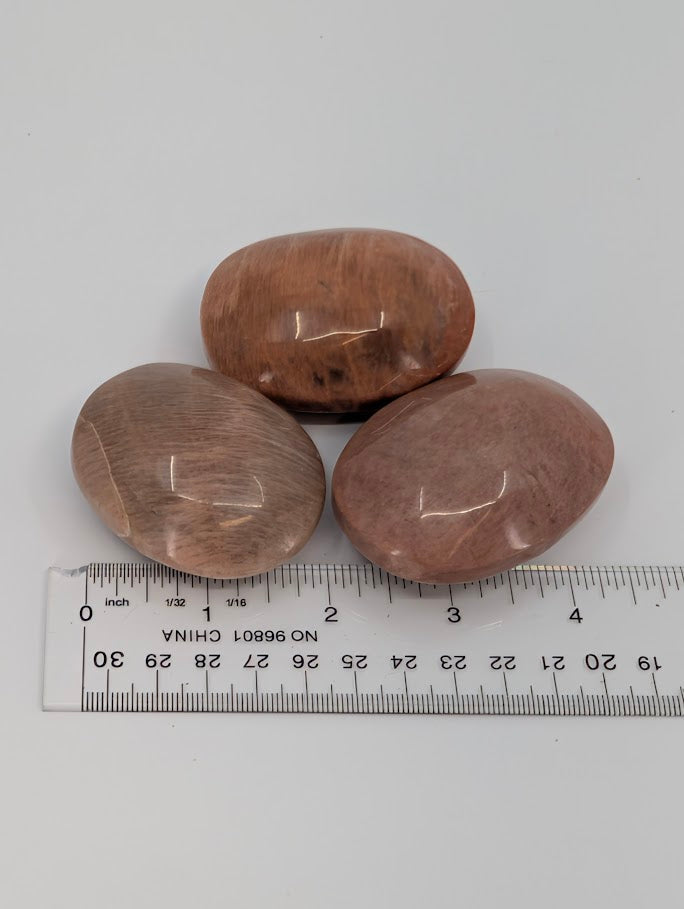 Peach Moonstone palm stones with measuring scale showing size and form