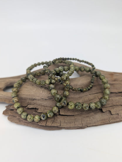 Set of peridot bracelets in 3.7, 5, 6, and 7 mm round beads on driftwood