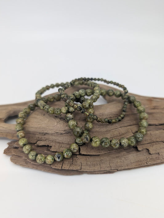 Set of peridot bracelets in 3.7, 5, 6, and 7 mm round beads on driftwood