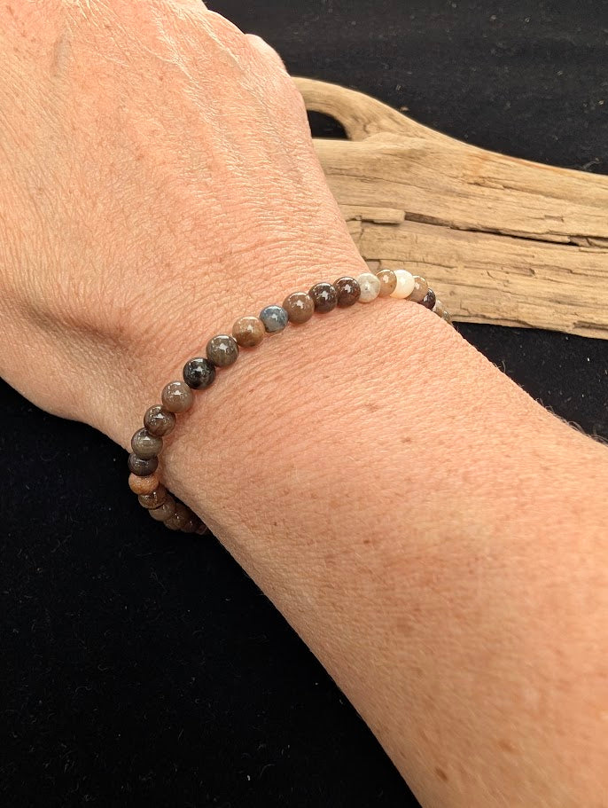 4mm polished Petrified Wood beaded stretch bracelet worn on a wrist for delicate size scale.