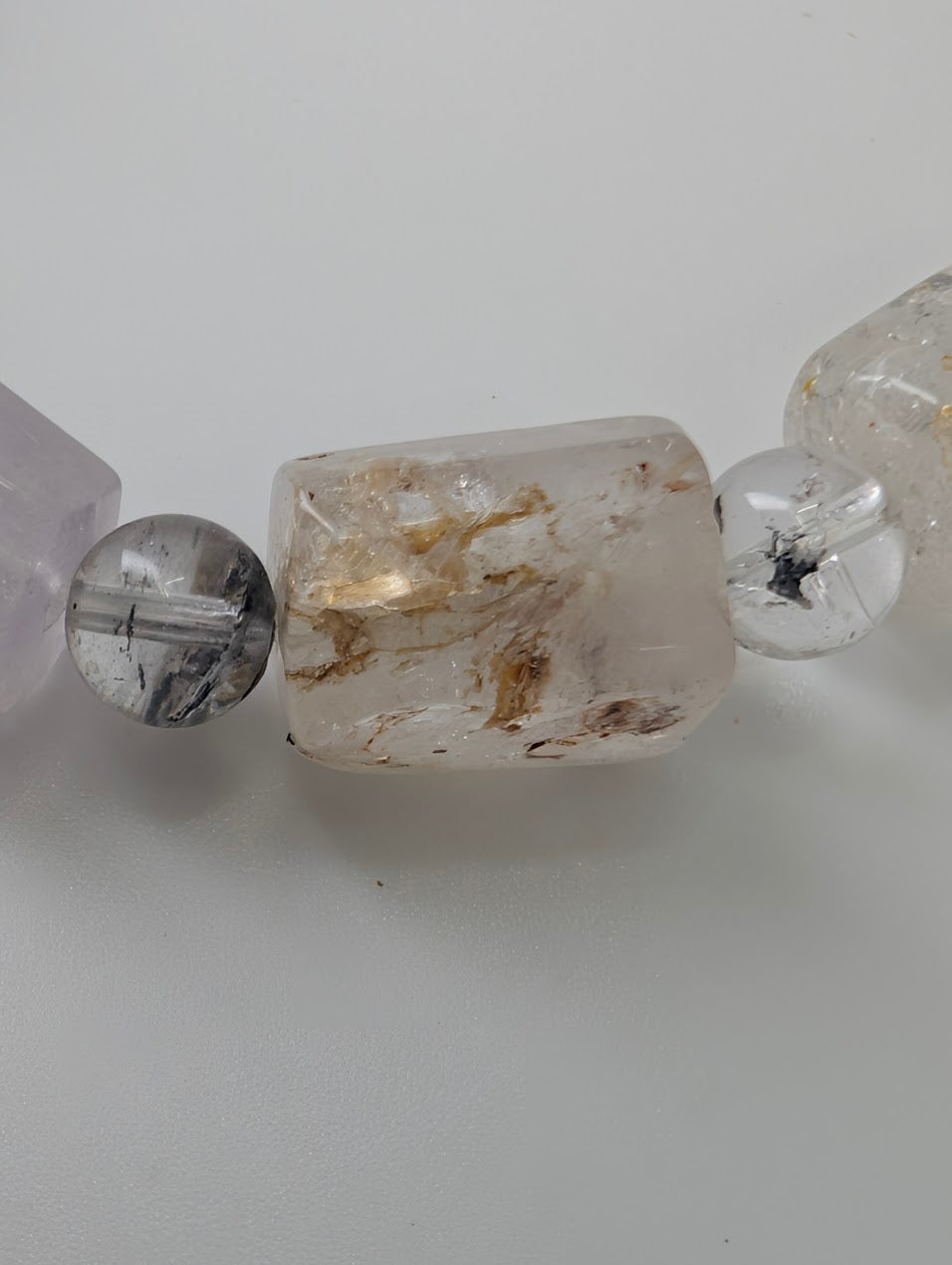 Close-up of clear quartz bead with golden petroleum inclusion.