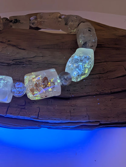 Petroleum quartz bracelet glowing under UV light showcasing fluorescence.