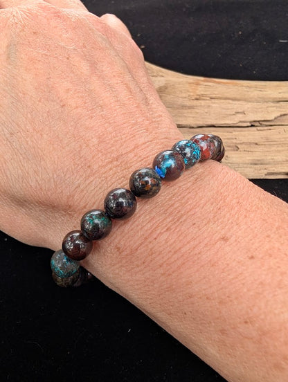 8mm polished Phoenix Stone beaded stretch bracelet worn on a wrist for size scale.