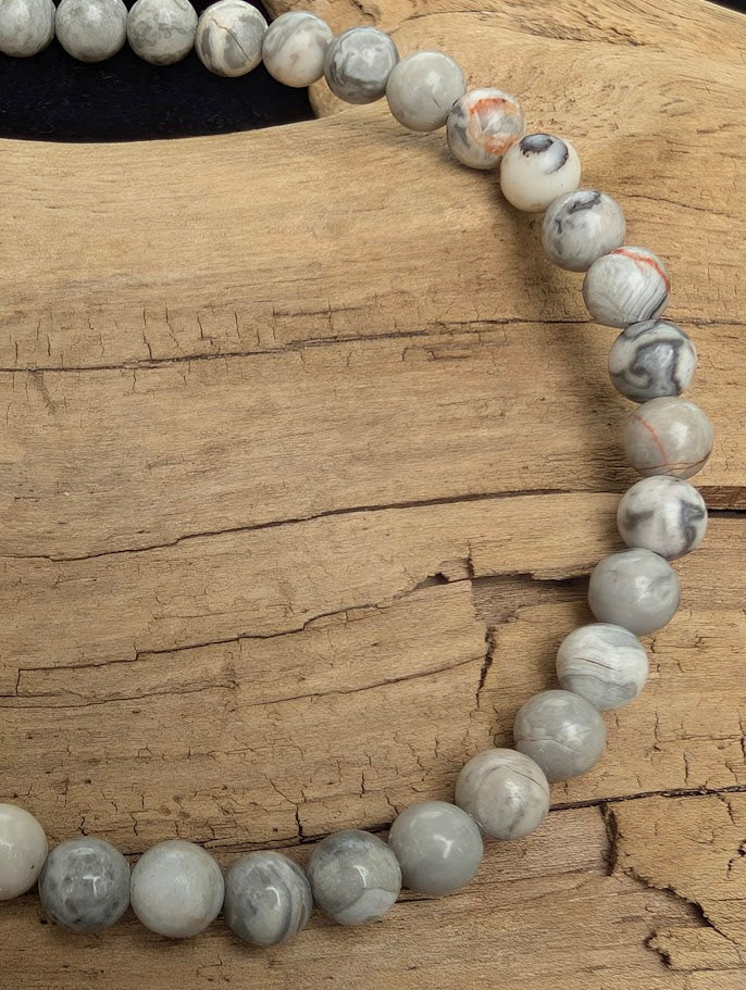 Macro close-up of 4mm polished Picasso Jasper beads highlighting the high-gloss finish and natural dark intersecting lines.