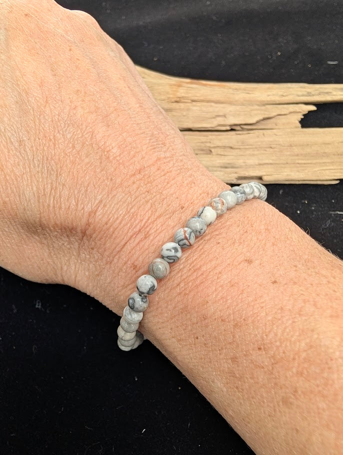 4mm polished Picasso Jasper beaded stretch bracelet worn on a wrist for delicate size scale.