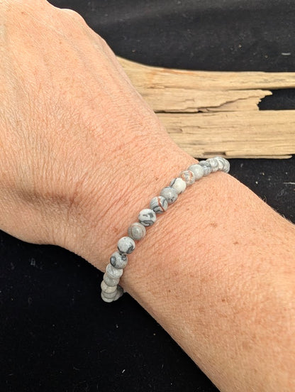 4mm polished Picasso Jasper beaded stretch bracelet worn on a wrist for delicate size scale.