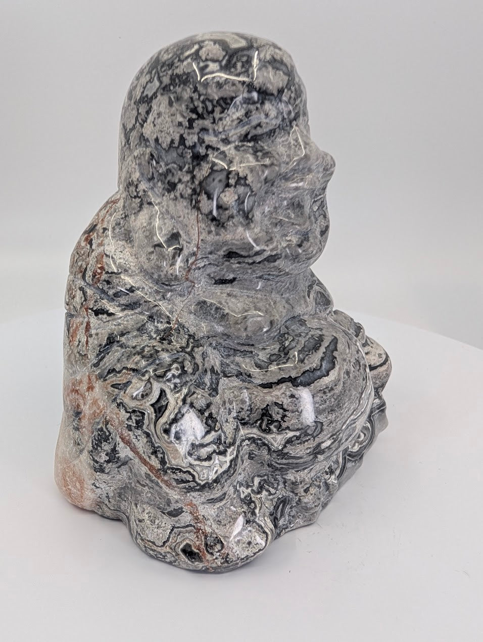 Side view of Picasso Jasper Laughing Buddha carving showing grey and black patterns