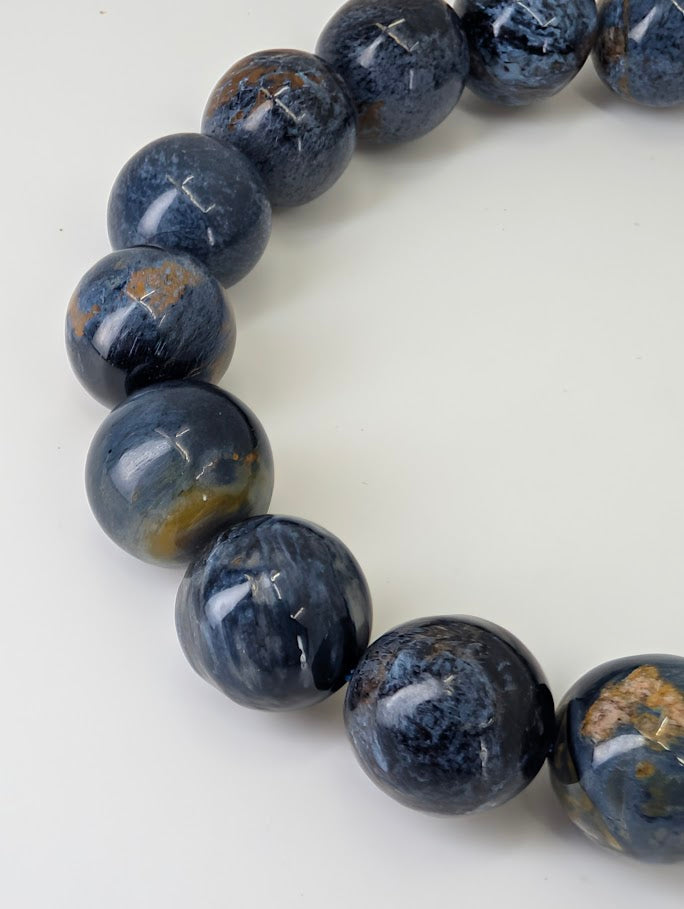 Macro close-up revealing chatoyant crocidolite fibers within blue Pietersite bead