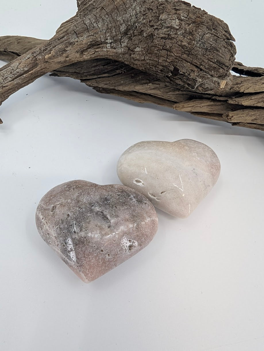 Pair of Pink Amethyst hearts showing soft beige and pink colors on driftwood.