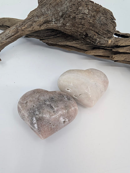 Pair of Pink Amethyst hearts showing soft beige and pink colors on driftwood.