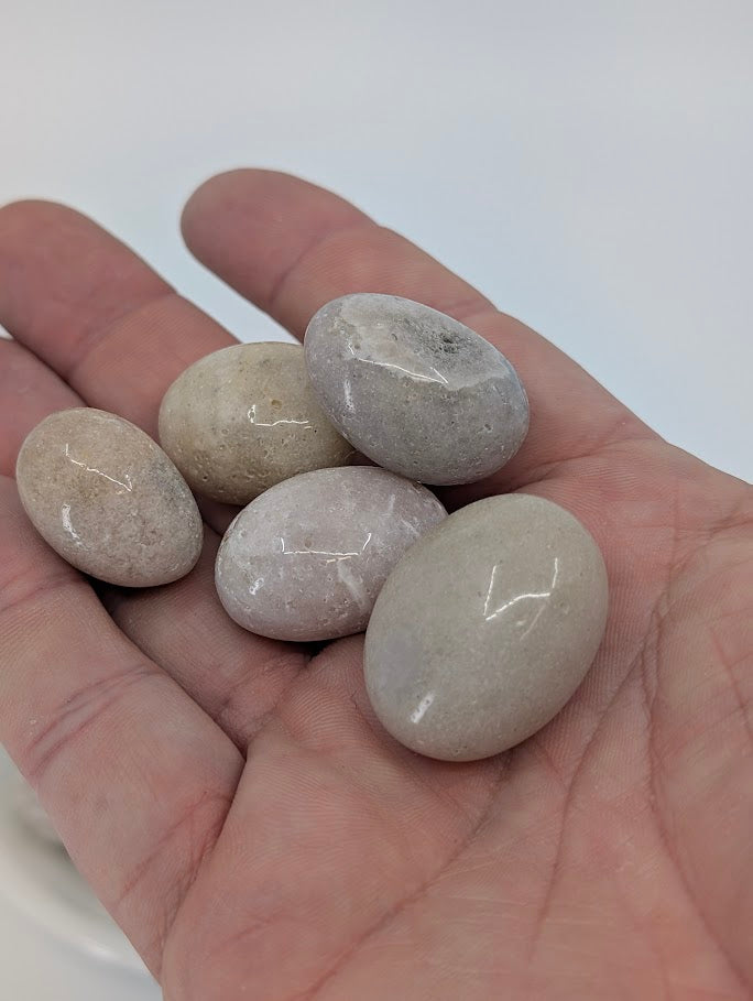 Pink Amethyst tumbled stones shown in hand for scale