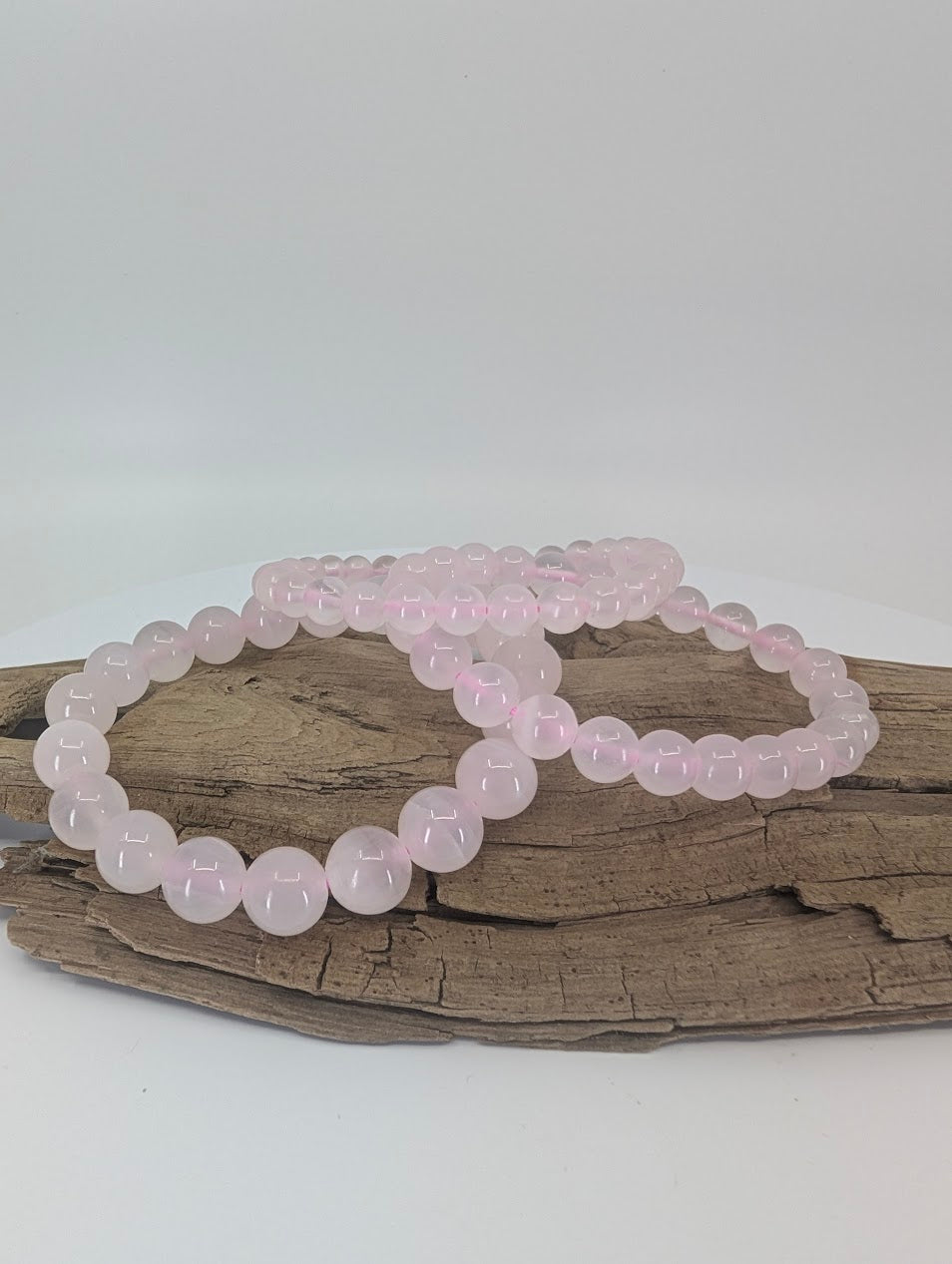 Natural Pink Calcite bracelets on driftwood showing soft pastel beads