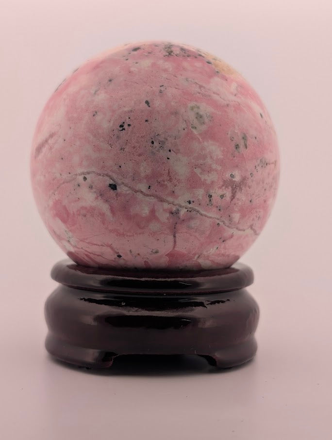 Polished rhodonite sphere close-up with black manganese inclusions