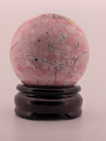 Polished rhodonite sphere close-up with black manganese inclusions