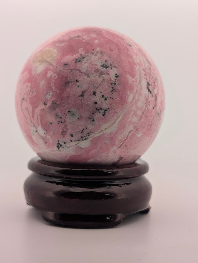 Rear angle of rhodonite sphere showing cream and pink mix