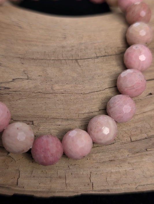 Macro close-up of 8mm faceted Pink Petrified Wood beads highlighting geometric surface cuts and fossilized grain patterns.