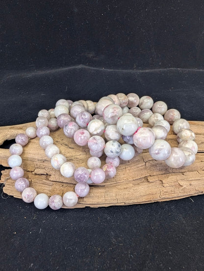 A collection of Pink Tourmaline (Rubellite) in Lepidolite matrix bracelets, showcasing the natural pink and grey heathered aesthetic across various sizes.