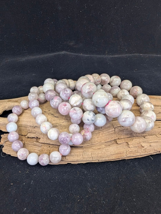A collection of Pink Tourmaline (Rubellite) in Lepidolite matrix bracelets, showcasing the natural pink and grey heathered aesthetic across various sizes.