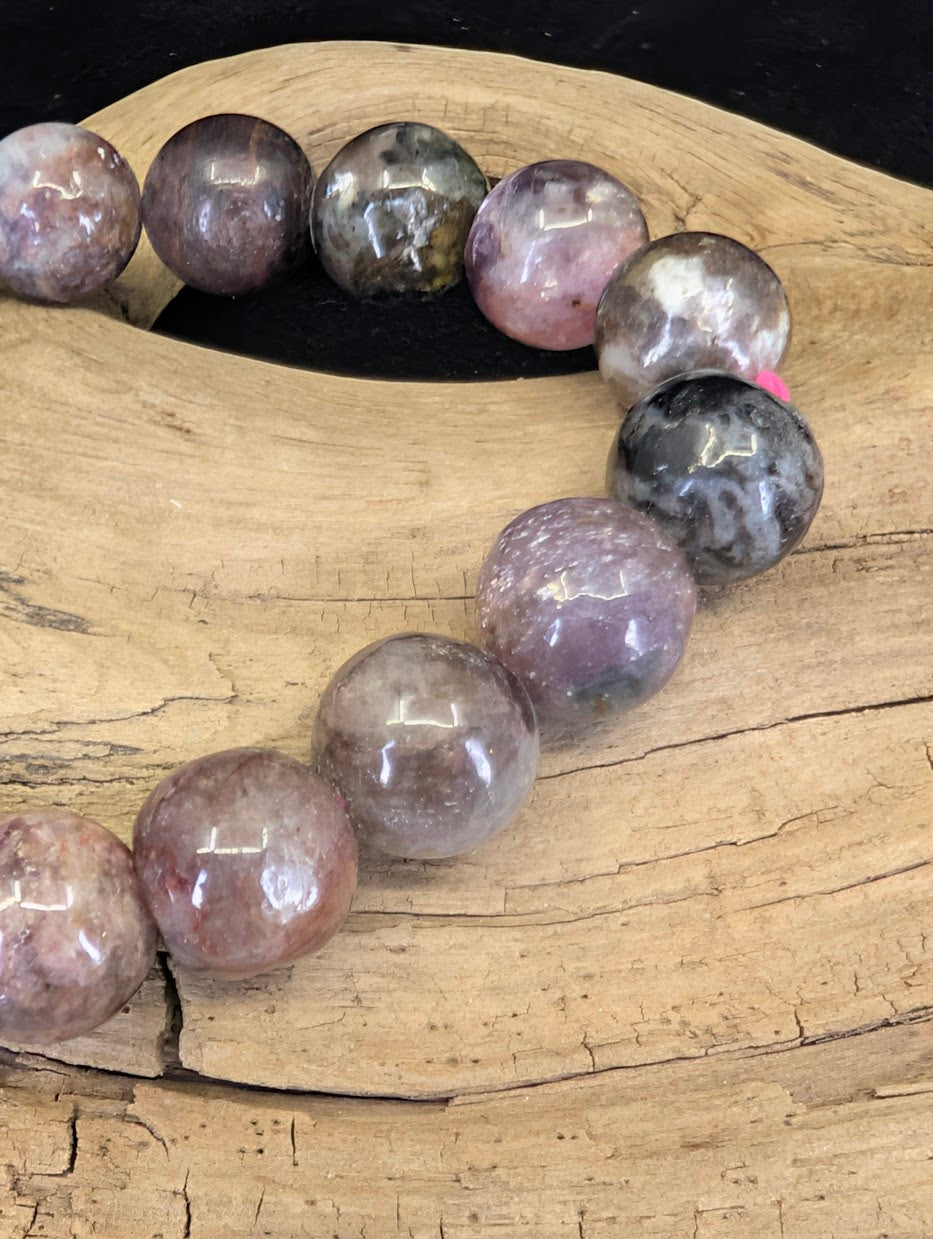 Close-up of 12mm Pink Tourmaline beads showing the natural lepidolite shimmer and smoky quartz inclusions.