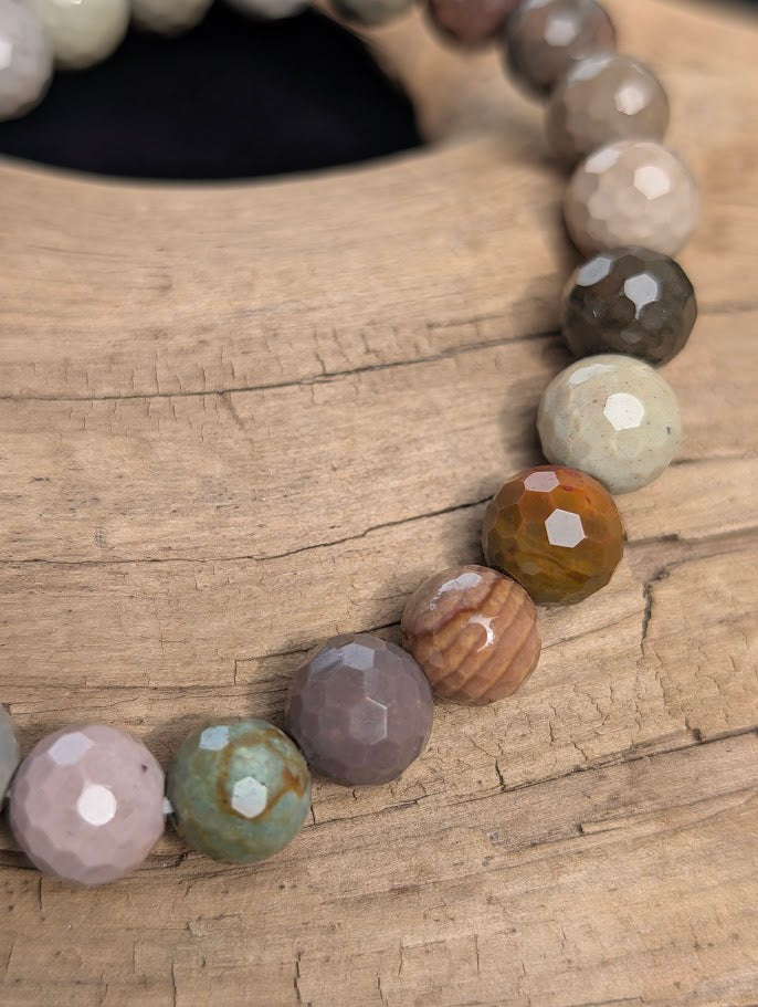 Macro close-up of 8mm faceted Polychrome Jasper beads highlighting geometric surface cuts and natural multi-coloured patterns.