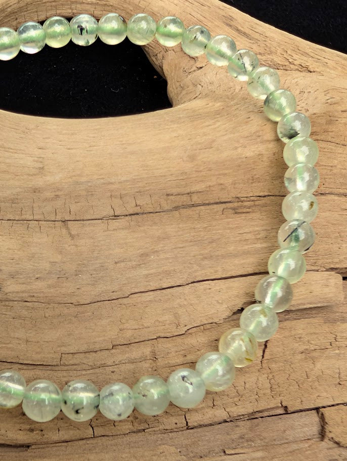 Macro close-up of 4mm polished Prehnite beads highlighting the translucent apple-green finish and dark needle-like Epidote inclusions.
