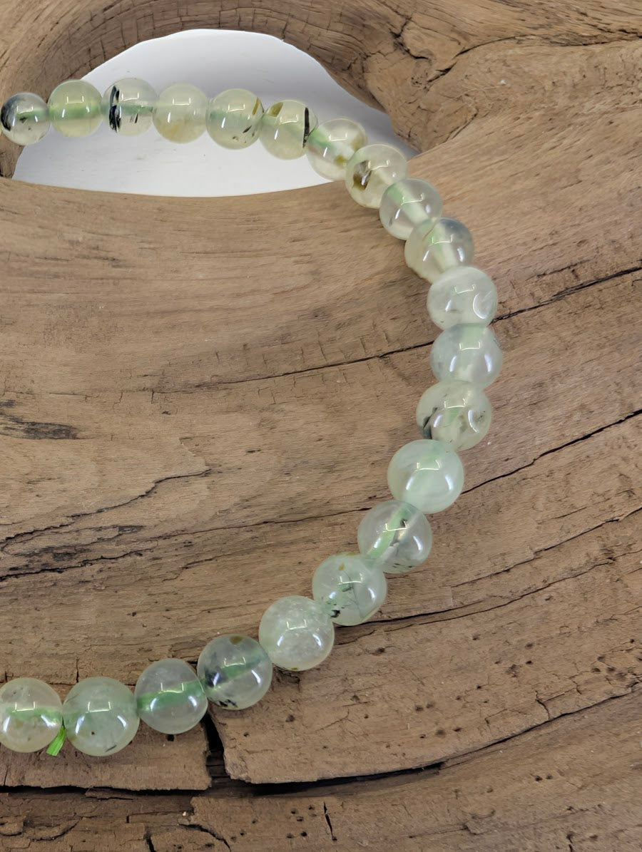 Close-up of 4.5mm Prehnite beads highlighting the natural pear-green translucency and dark Epidote needles.