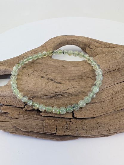 4.5mm Prehnite bracelet with Epidote inclusions from South Africa shown on natural wood.