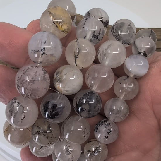 Discover the natural beauty of dendritic quartz. Each bracelet reveals unique manganese oxide “forest” inclusions suspended inside clear quartz, creating miniature landscape scenes within every bead. Available in 8 mm, 14 mm, 15 mm, and 16 mm sizes, these bracelets are all-natural, one-of-a-kind, and crafted from high-quality bead-grade quartz. A perfect blend of grounding energy and geological artistry.