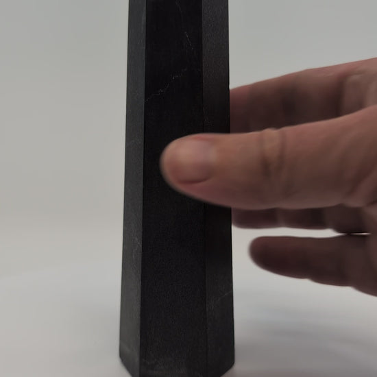 Close-up video of glossy 440g Shungite tower showing carbon texture and reflective graphite finish.