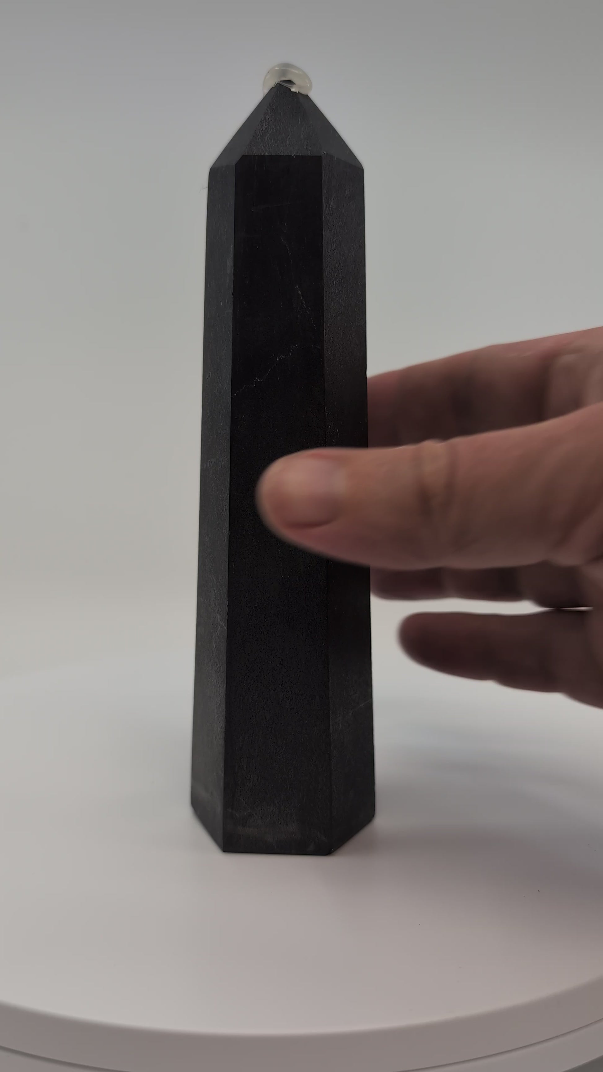 Close-up video of glossy 440g Shungite tower showing carbon texture and reflective graphite finish.