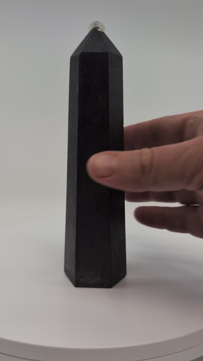 Close-up video of glossy 440g Shungite tower showing carbon texture and reflective graphite finish.