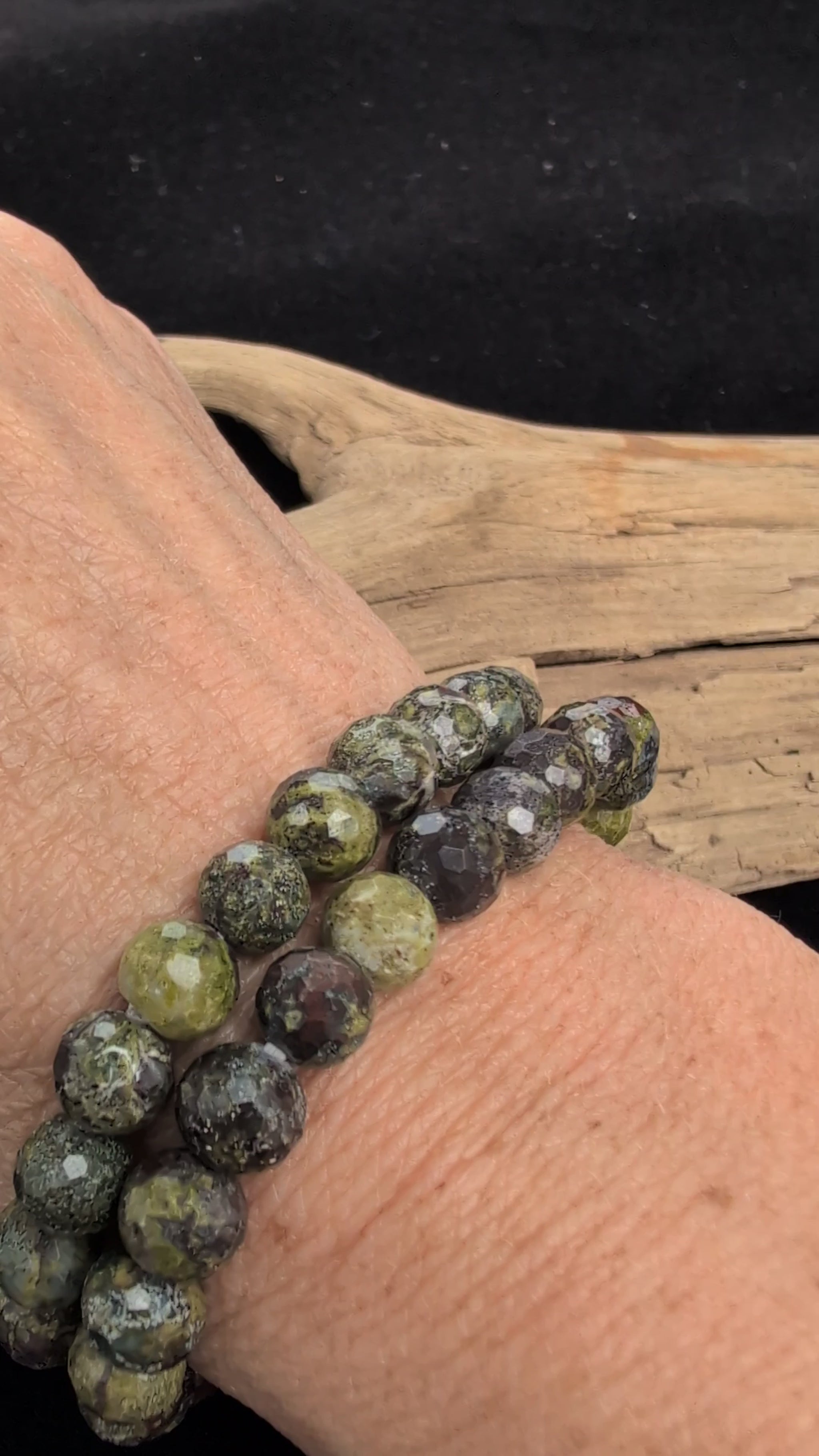 Video showcasing the highly reflective faceted texture and natural green and red mottled patterns of an 8mm Dragon Blood Stone beaded stretch bracelet worn on a wrist.