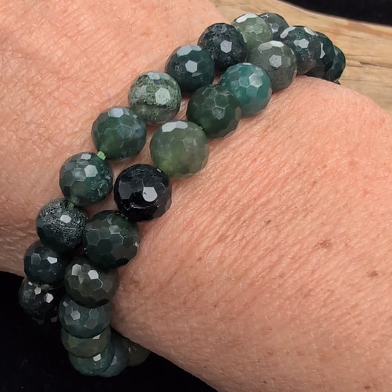 Video demonstrating the 8mm faceted Moss Agate beaded stretch bracelet in motion, highlighting the light-catching geometric cuts and the deep green dendritic moss formations suspended within the stones.
