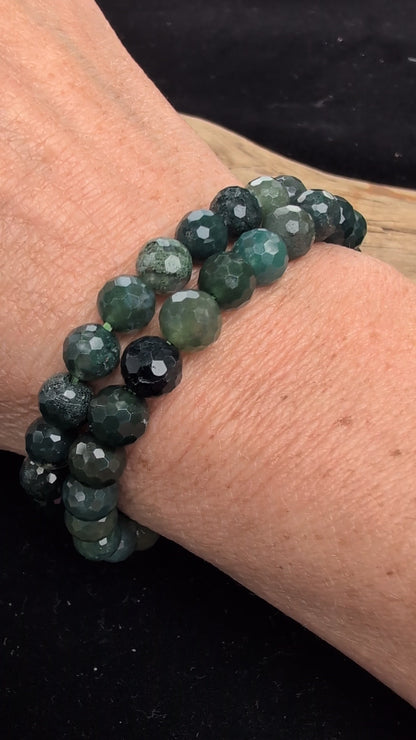 Video demonstrating the 8mm faceted Moss Agate beaded stretch bracelet in motion, highlighting the light-catching geometric cuts and the deep green dendritic moss formations suspended within the stones.